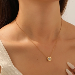Gold necklace with Roman numeral round pendant and zircon, shown worn by a model