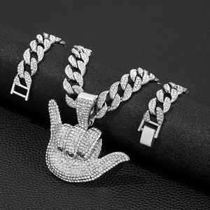 Macro shot of silver hip-hop jewelry set with paved crystals on black leather background