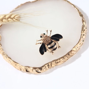 Vintage gold bee brooch with brown crystals and black enamel on a white coaster
