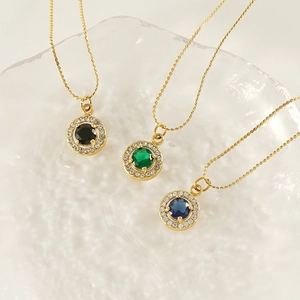 Detailed view of three 18K gold necklaces with black, green, and blue zircon pendants