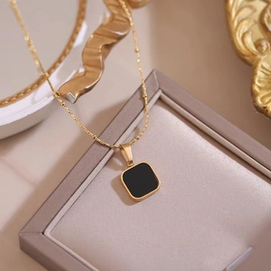 Detail of square black onyx pendant on gold bead chain against a vintage display