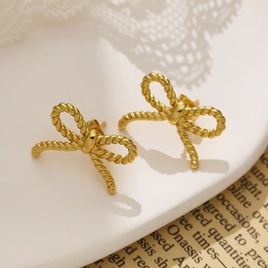 Detail of gold bow earrings with twisted rope texture on a white display tray