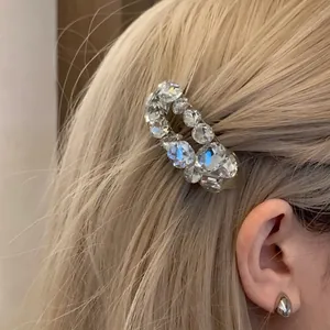 Sparkling oval zircon hair clip with silver setting worn on blonde hair by a model