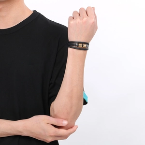 Detail of men's multilayer black braided leather bracelet with textured gold metal beads