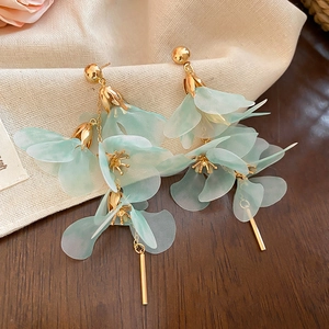 Détail de longues boucles d'oreilles florales avec pétales en maille vert clair et dorés