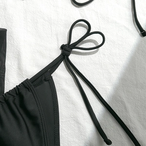 Detail shot of black bikini top featuring a unique heart-shaped knot on the thin strap