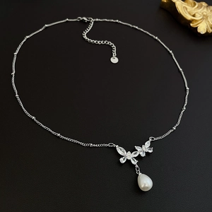 Detailansicht der silbernen Zirkonia-Schmetterling-Kette mit einer weißen Tropfenperle