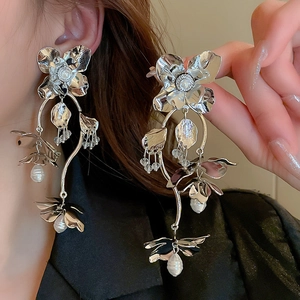 Boucles d'oreilles fleurs argentées avec pétales métalliques et perles sur un modèle