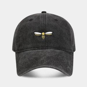 Close-up of vintage washed grey baseball cap with detailed bee embroidery and denim texture
