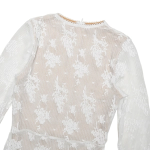Détail de la dentelle florale blanche et du col rond sur une robe longue moulante