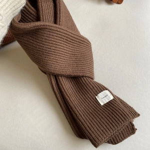 Close-up of brown ribbed knit scarf showing thick warm texture and branding label