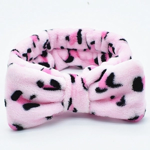 Close-up of pink leopard print coral fleece headband with soft plush bow detail