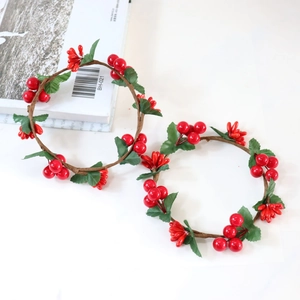 Christmas candle ring with artificial red berries and green leaves on white background