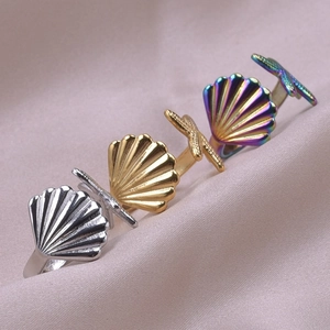 Macro detail of polished stainless steel starfish and seashell rings on soft silk fabric