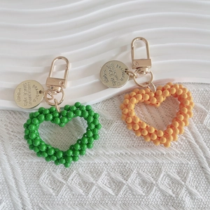 Handmade woven pearl heart keychains in green and orange with engraved gold metal charms