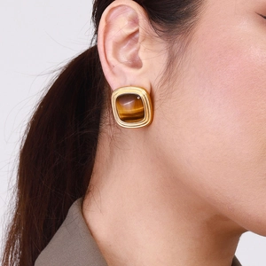 Close-up of model wearing gold square earrings with tiger eye stone inlay detail