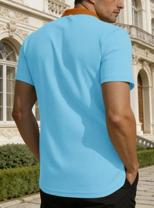 Polo bleu clair coupe ajustée avec col orange présenté devant une arche classique
