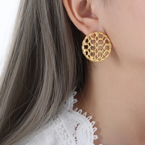 Vintage hollow woven round earrings in gold titanium steel on a female model