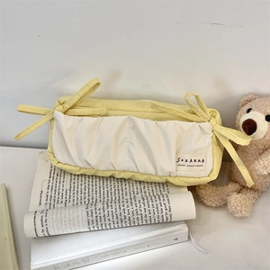 Detailed close-up of yellow and white fabric stationery pouch with side ribbon ties