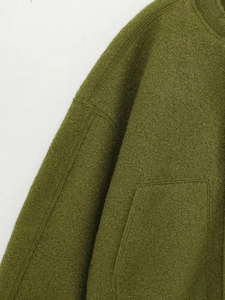 Detail view of olive green bomber jacket showing stitching and textured boucle fabric