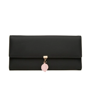 Macro detail of black PU leather wallet featuring a pink leaf pendant and silver text