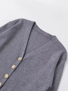 Detail of dark gray knit cardigan featuring golden embossed metal buttons and V-neckline