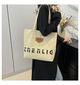 Model wearing a large off-white canvas tote bag showing its size and capacity