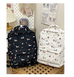 Detail of cute graffiti backpacks with dachshund prints and blue bows on a wooden stool