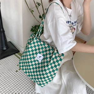 Detail view of green and white checkered corduroy tote bag worn over the shoulder