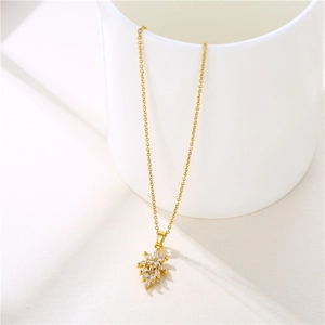 Collier minimaliste en acier doré avec pendentif feuille étincelante sur fond blanc