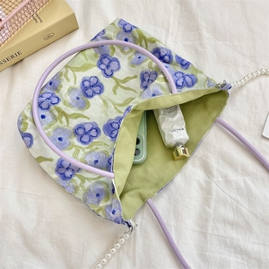 Detail of floral tote bag with purple ring handles, pearl chain, and green canvas lining