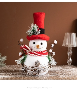 Close-up of a white snowman ornament with a red top hat and striped scarf on a rattan base