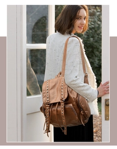 Detailed view of brown washed leather backpack with metal rivets and vintage texture