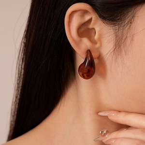 Gros plan de boucles d'oreilles goutte en résine ambre avec texture marbrée brune