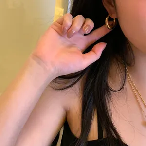 Detail of chunky gold hoop earring with minimalist design worn by a model in warm light