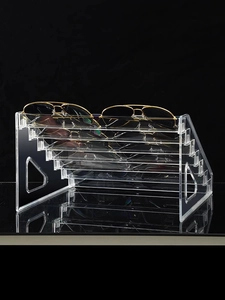 Macro view of 6-tier clear acrylic tiered sunglasses display stand on black background