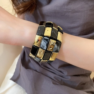 Detail of geometric acrylic checkerboard bracelet with black gold and marble patterns