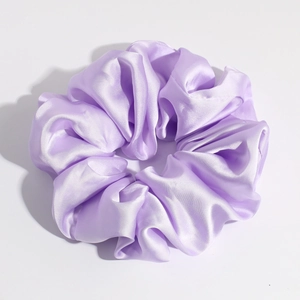 Close-up of light purple satin scrunchie with soft silk luster and elastic fold detail
