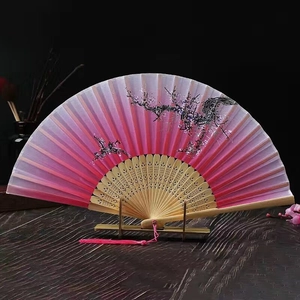 Close-up of pink gradient silk fan with bamboo carvings and decorative tassel