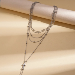 Detail of layered silver chain necklace with beaded accents and a sparkling zircon cross pendant
