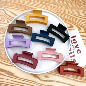 Detailed view of large matte rectangular hair claws in eight assorted colors on a ceramic tray