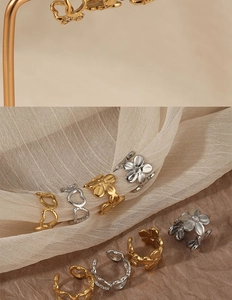 Macro shot of gold and silver hollow heart and flower ear clips on soft tulle fabric