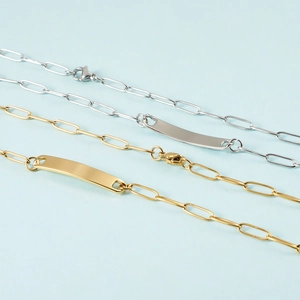 Detail of silver and gold paperclip chain necklaces with blank rectangular bar pendants