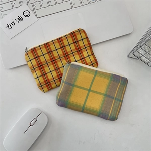 Vue à plat de pochettes à monnaie en toile à carreaux avec fermetures en métal sur bureau