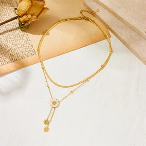 Double-layered gold clover necklace with snake chain and tassel on vintage book background