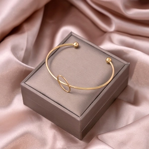Detailed view of a gold geometric open bangle resting on a luxury jewelry box with satin