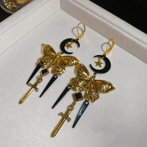 Détail de boucles d'oreilles rétro françaises avec lune dorée, papillon et poignard
