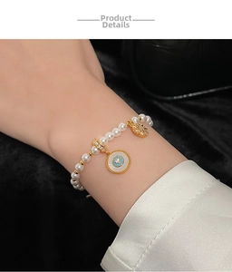 Détail d'un bracelet en perles avec breloques dorées en zircone porté au poignet