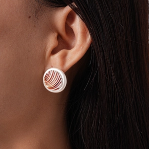 Macro detail of vintage geometric round earring with orange radial texture grooves on model