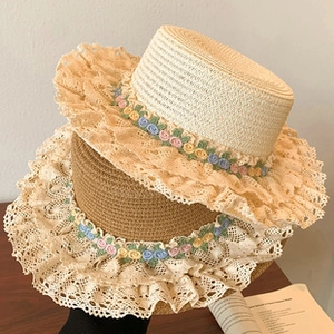 Detail of wide-brim straw sun hats featuring elegant lace trim and colorful floral embroidery